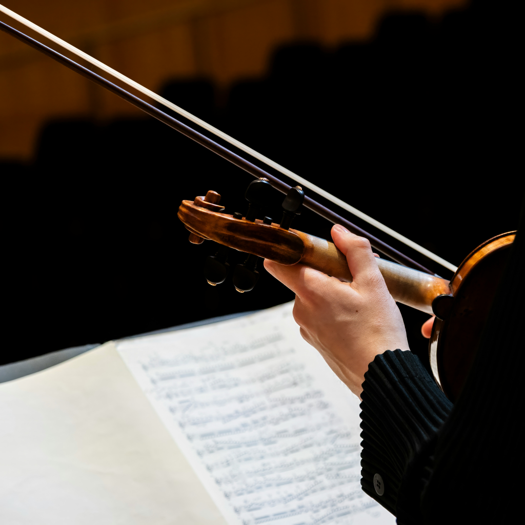 Person holding violin in rest position with sheet music