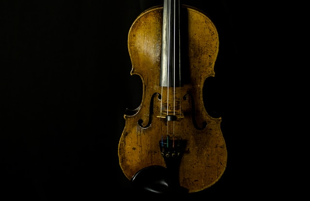 Old beat up violin against a black background